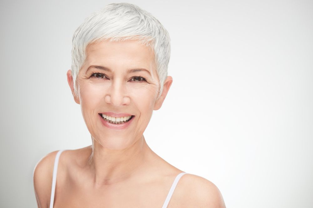 Smiling Woman With Short White Hair in a White Top — Fraser Shores Hair Design In Urraween, QLD