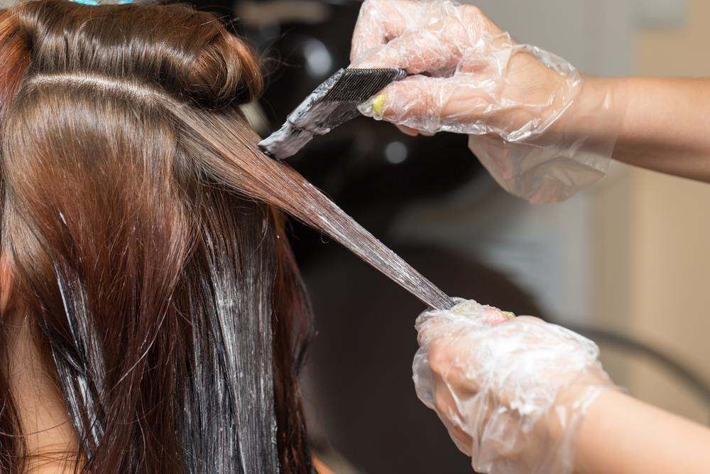 Hair Stylist Applying Dye to Long Brown Hair with A Brush and Gloved Hands — Fraser Shores Hair Design In Urraween, QLD