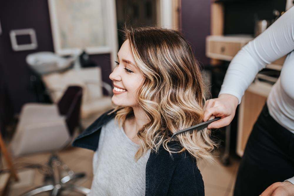 Smiling Woman Getting Her Hair Styled in A Salon — Fraser Shores Hair Design In Urraween, QLD