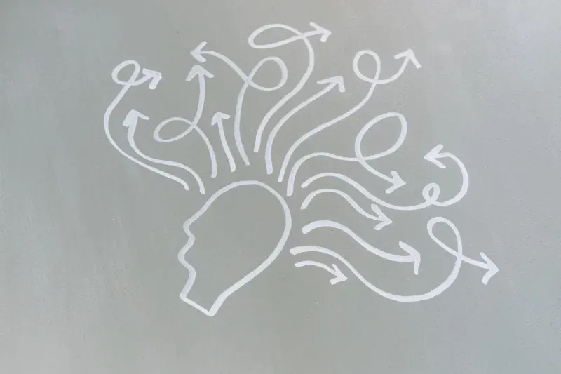 White line drawing of a human head with swirling arrows and circles above it, suggesting ideas or confusion