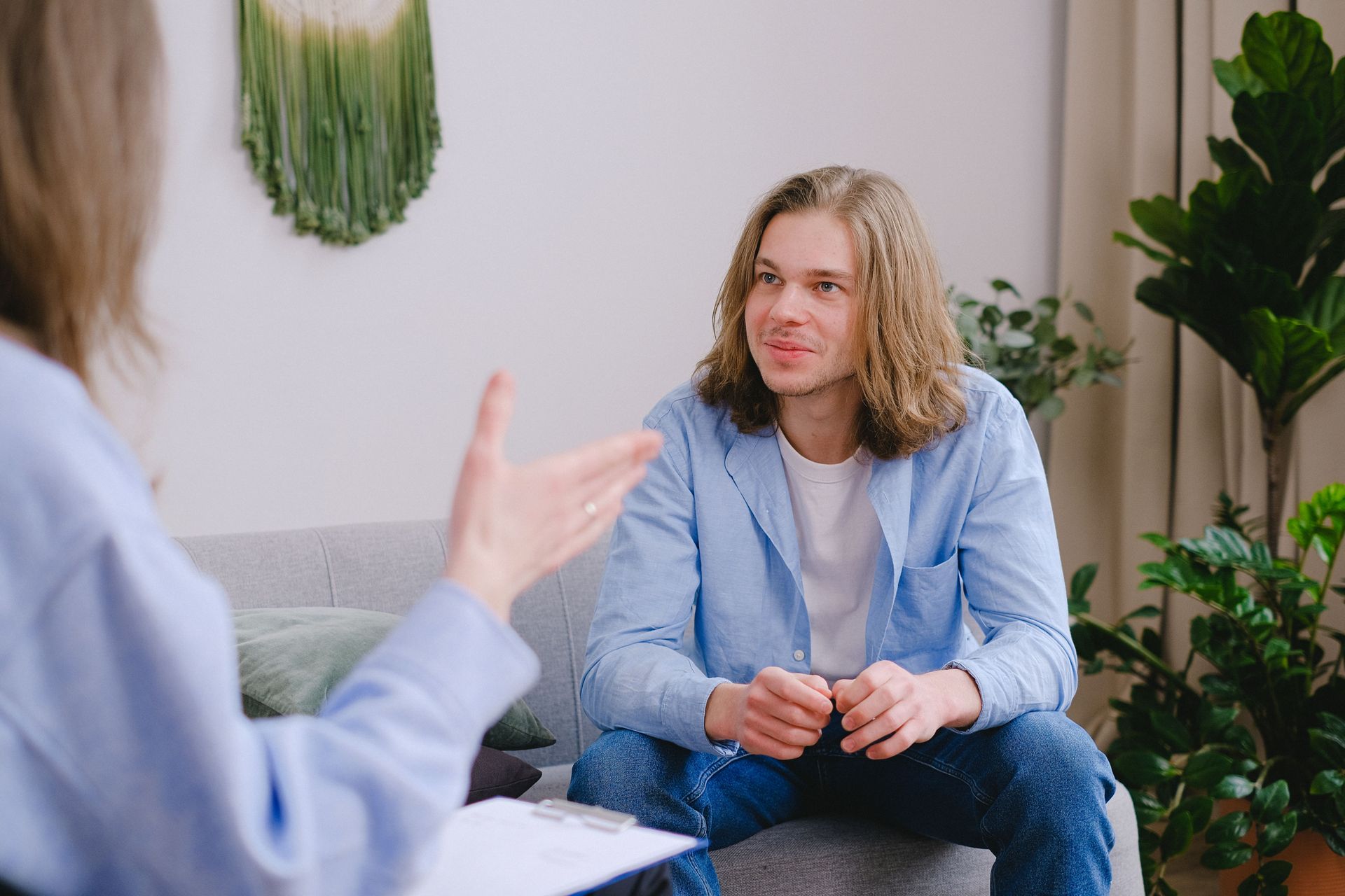 Two people talking in a counseling session, one gesturing while the other listens on a couch.