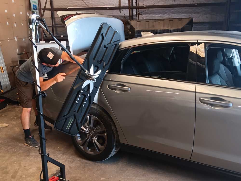 Mechanic inspecting a light blue car door in a garage.