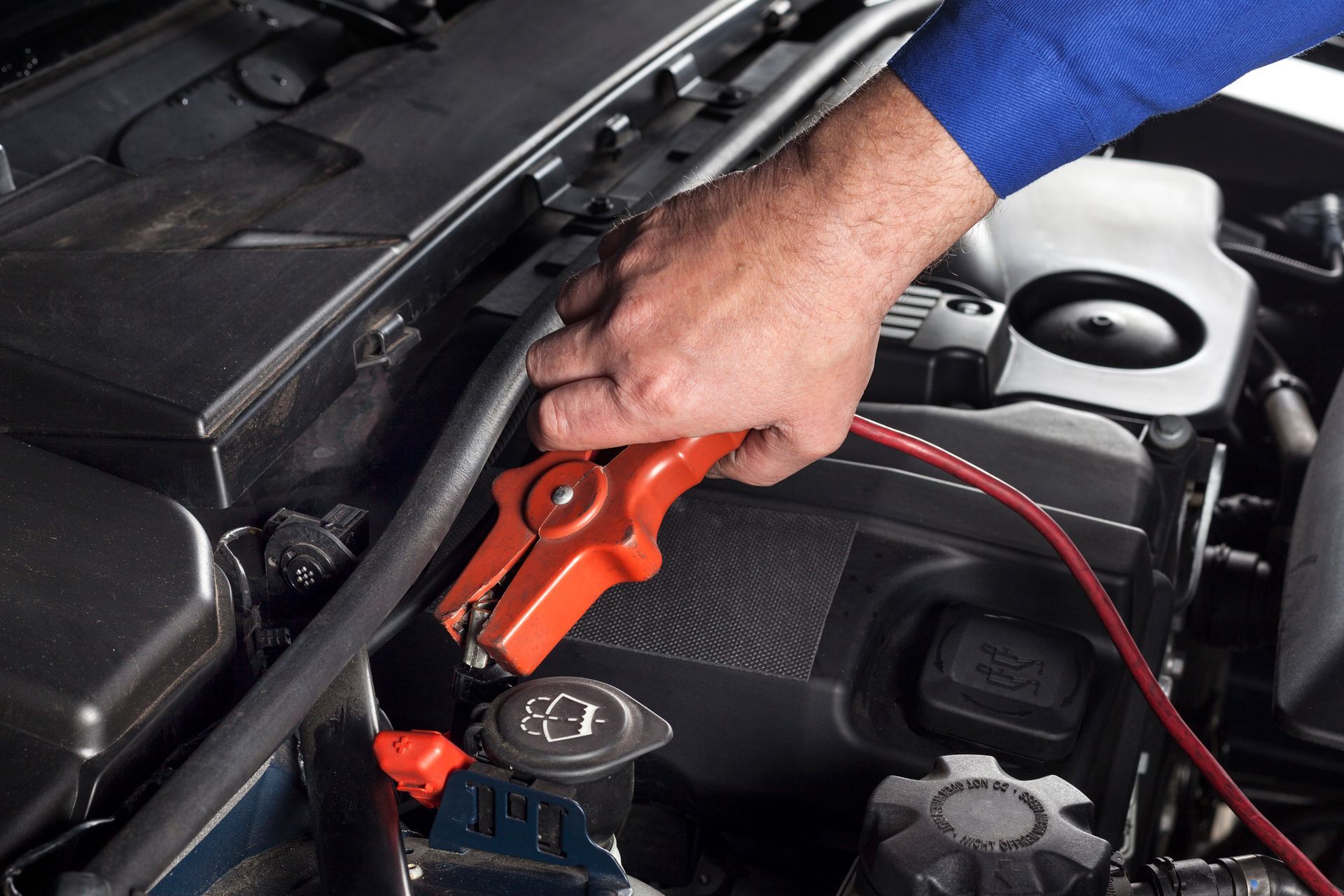 Close-up of a hand using a cable to jumpstart a car.