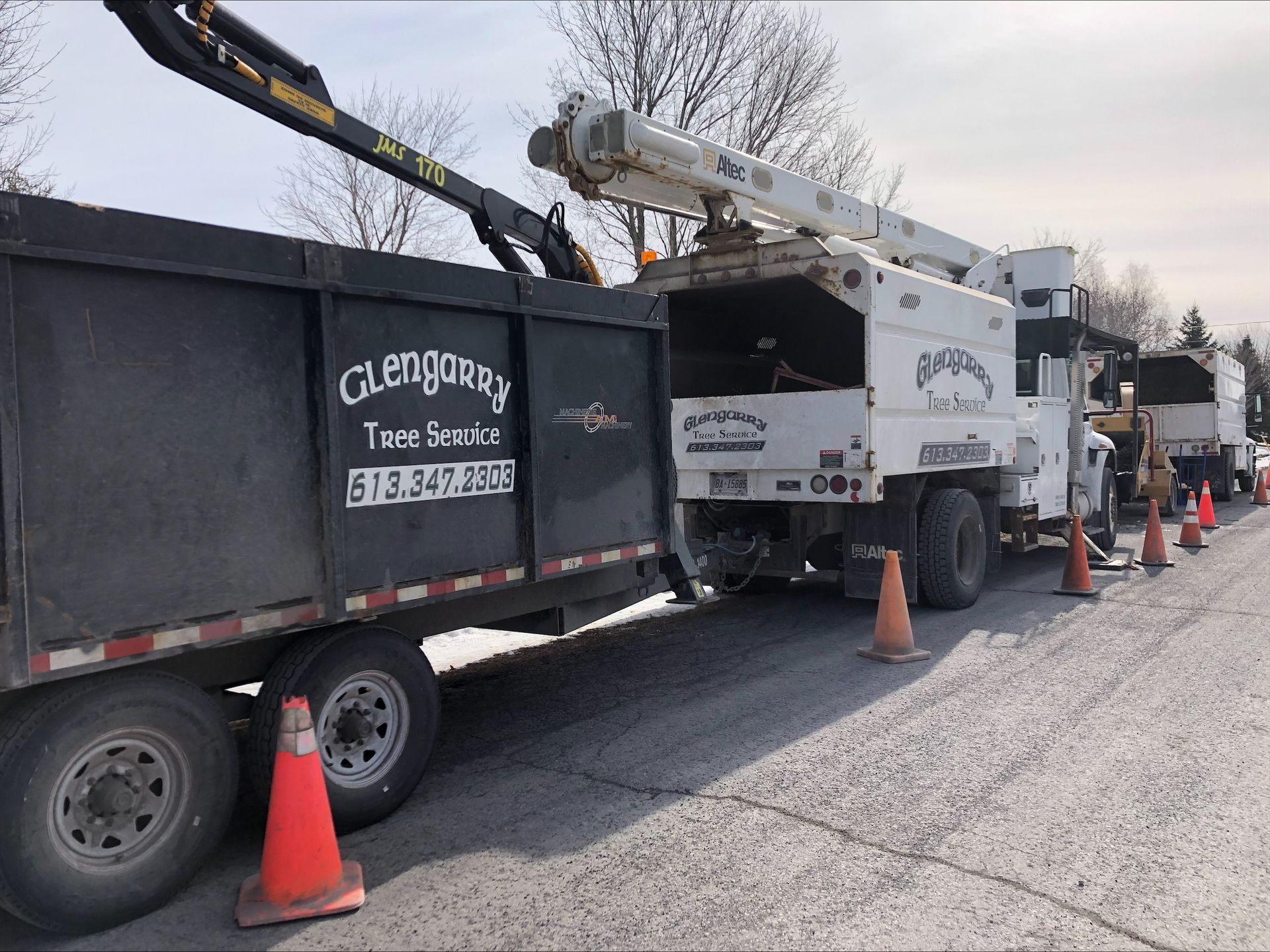 Tree service truck with attached trailer and cones along the road, 