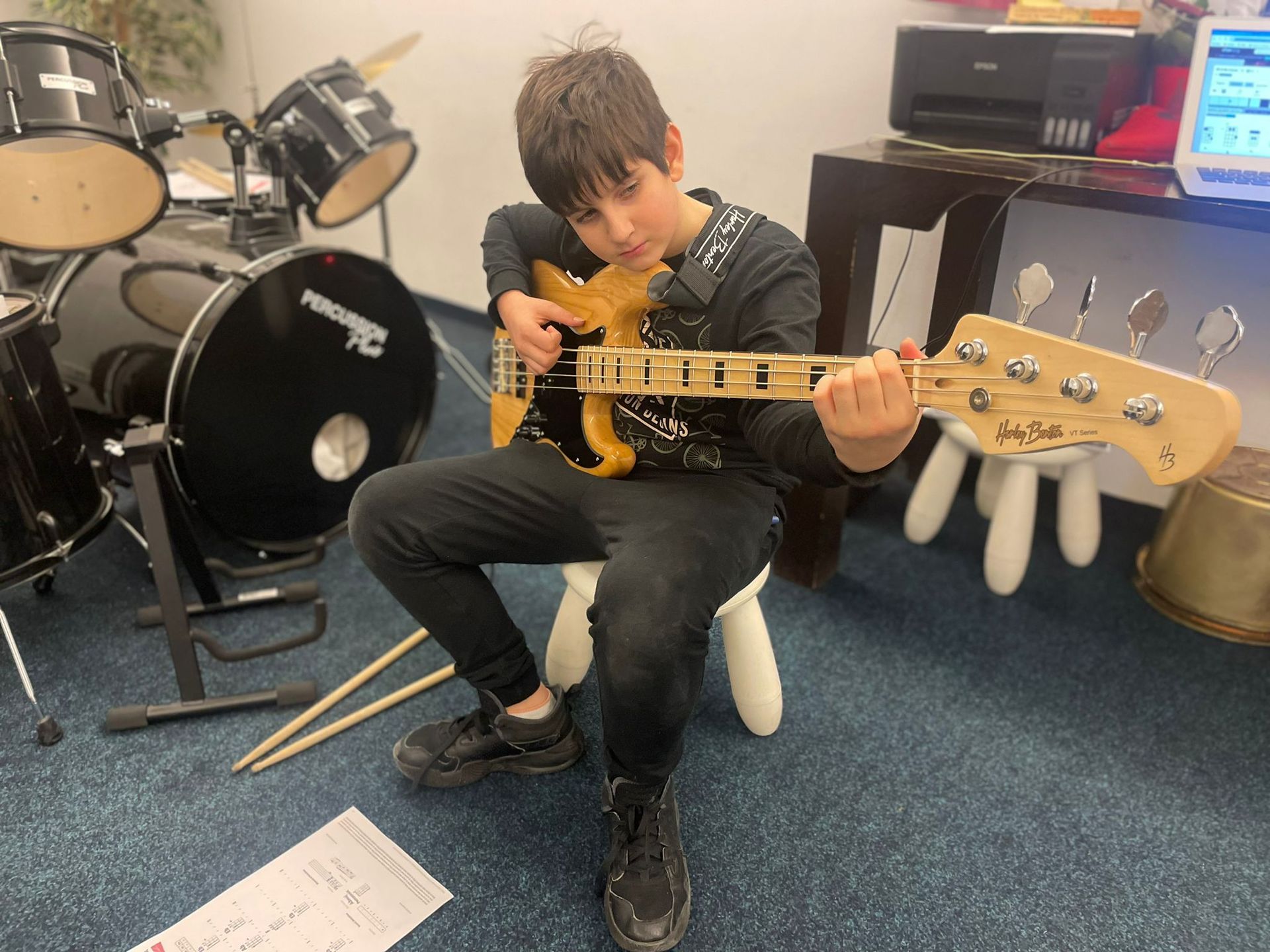 A young boy is sitting on a chair playing a guitar.