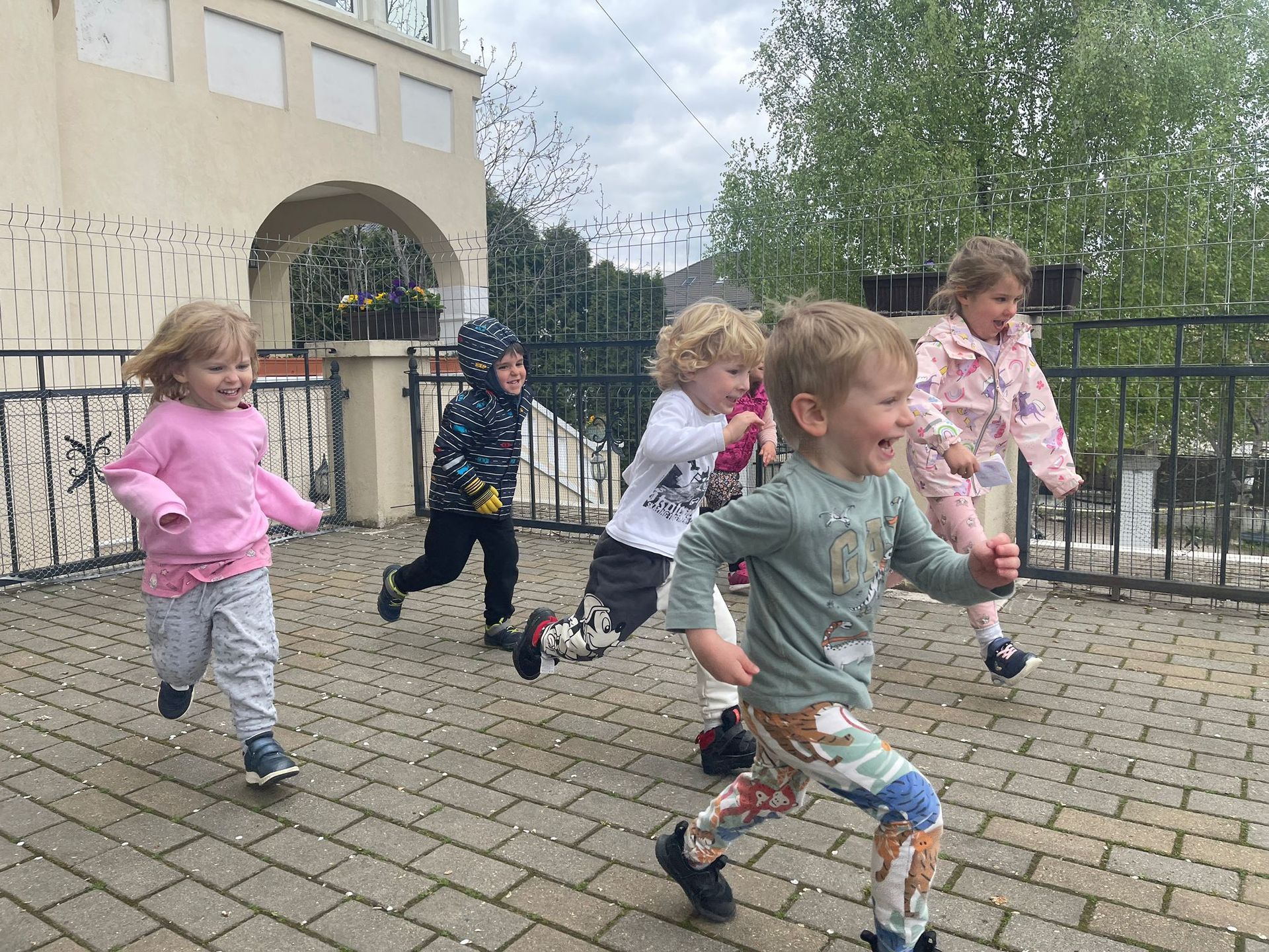 A group of children are running on a brick sidewalk.