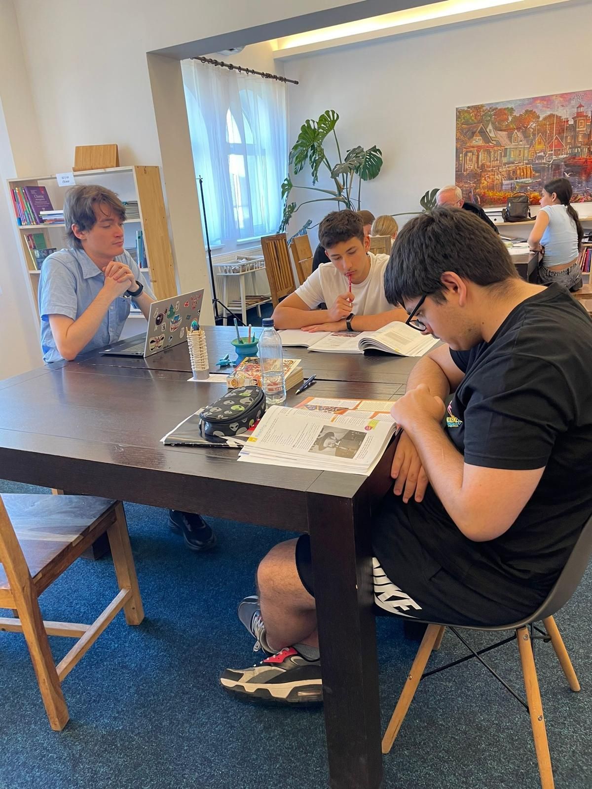 A group of people are sitting at a table reading books.