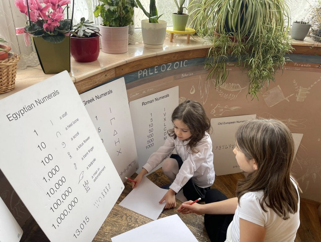 A group of Montessori Cluj kindergarden children are sitting at a table in a classroom.