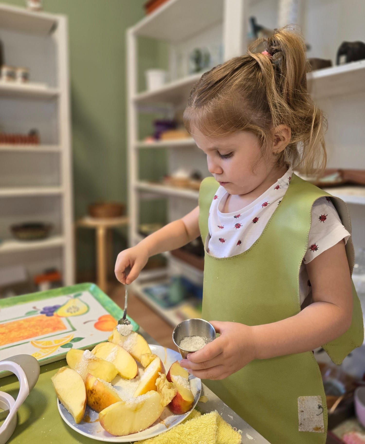 A little girl is cutting apples on a plate with a fork.