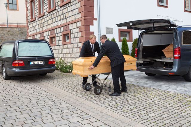 Würdevolle Abläufe bei Bestattungen Emmerling Tim Dölzer und ein Mitarbeiter bei Bestattungen Emmerling tragen einen Sarg zum Fahrzeug
