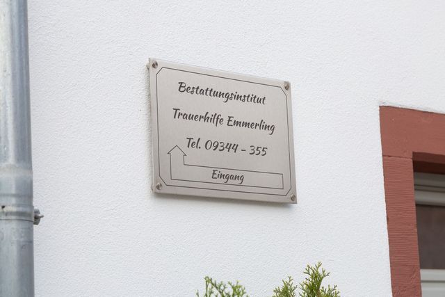 Das Schild weist den Weg zum Bestattungsinstitut – Trauerhilfe Emmerling in Großrinderfeld/ Gerchsheim. Eingangsschild „Bestattungsinstitut Trauerhilfe Emmerling“ in Großrinderfeld/ Gerchsheim