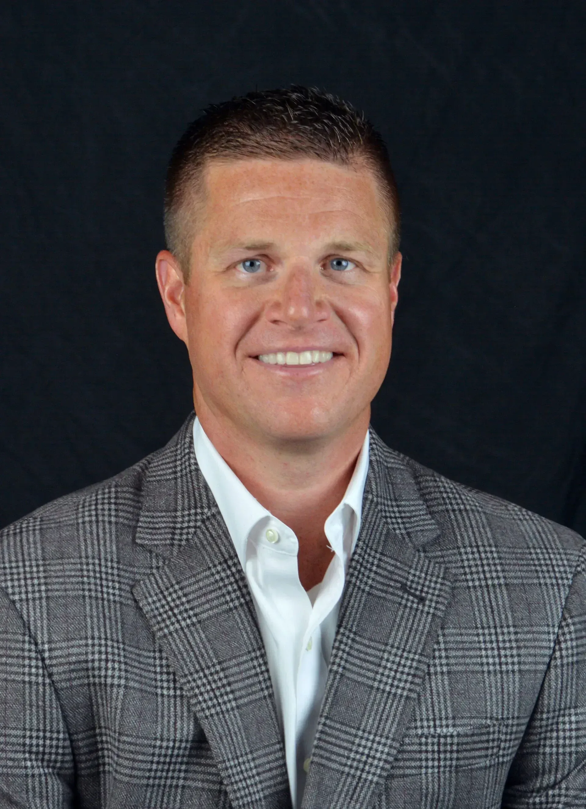 A man in a suit and white shirt is smiling for the camera.