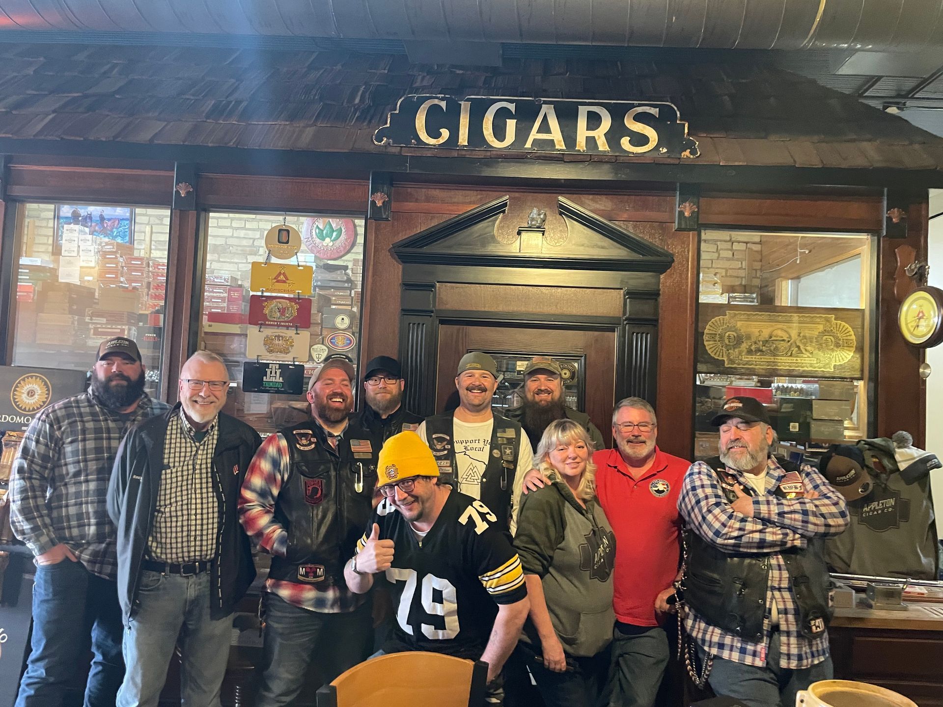 A group of men are posing for a picture in front of a store called cigars.