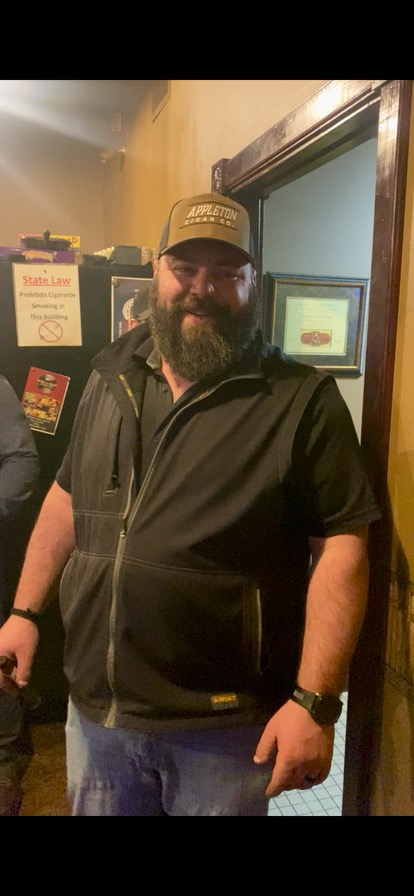 A man with a beard and hat is standing in a doorway.