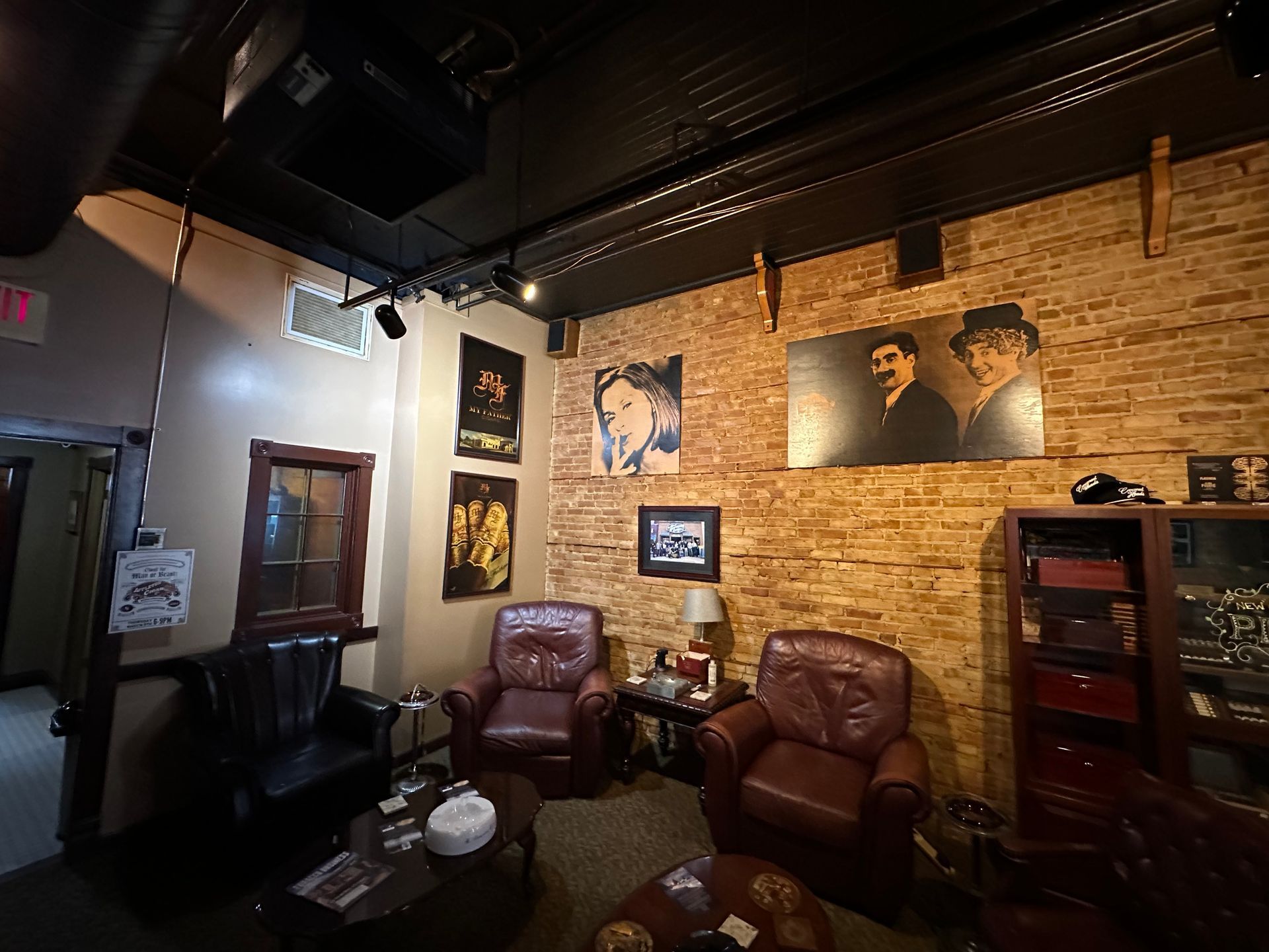 A cigar lounge with chairs , a table , and a brick wall.
