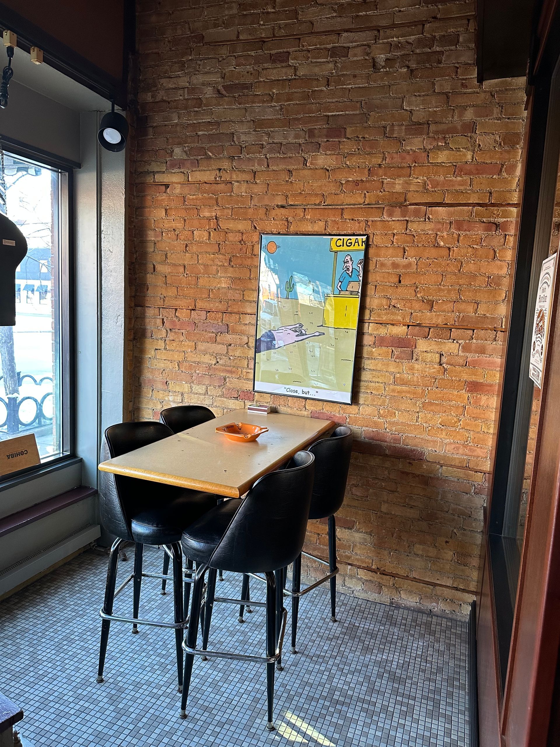 A room with a table and chairs in front of a brick wall.
