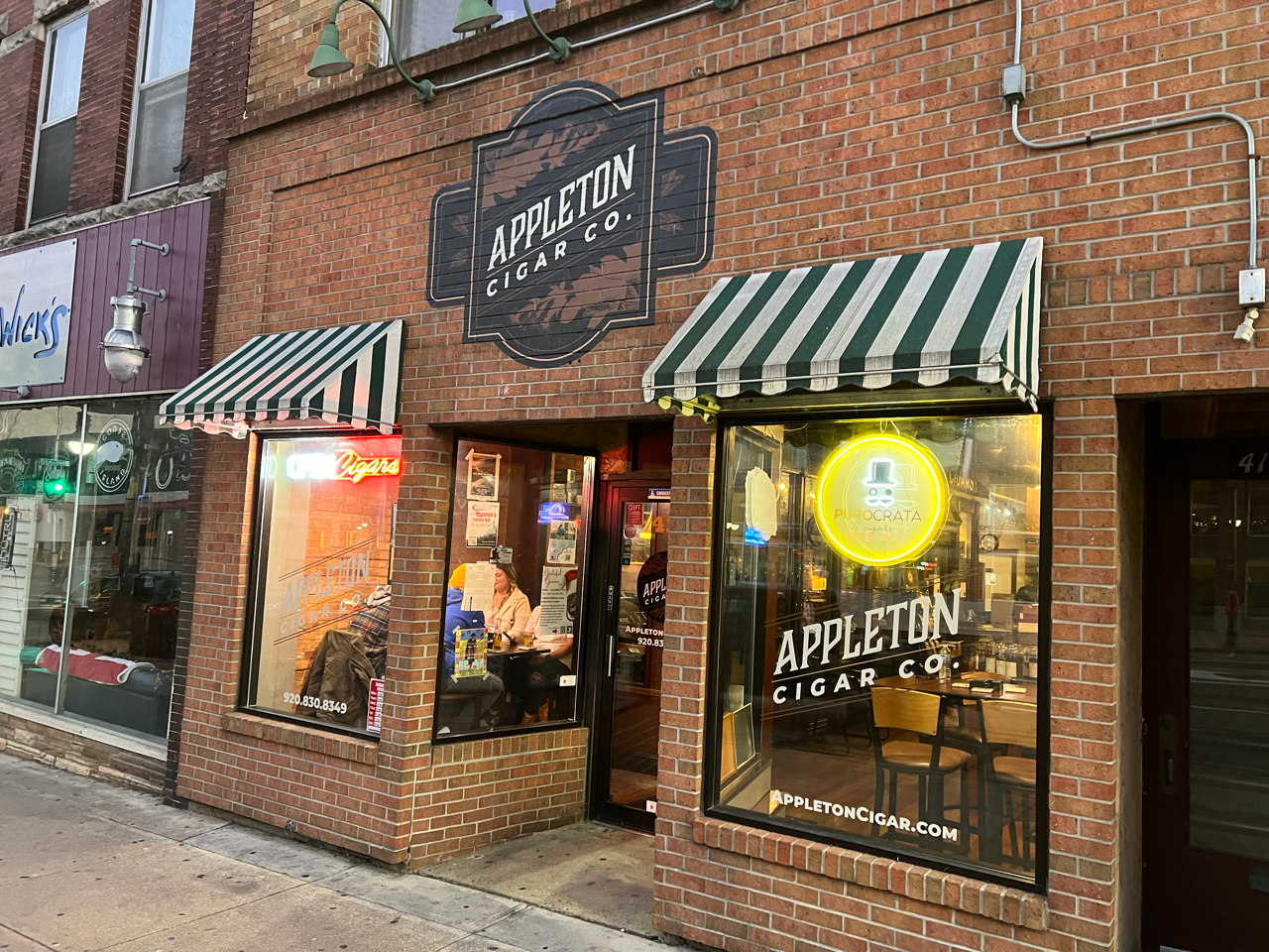 A brick building with a green and white awning on the front of it.
