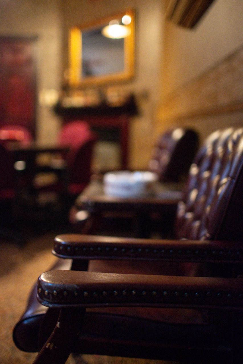 A chair in a dark room with a fireplace in the background