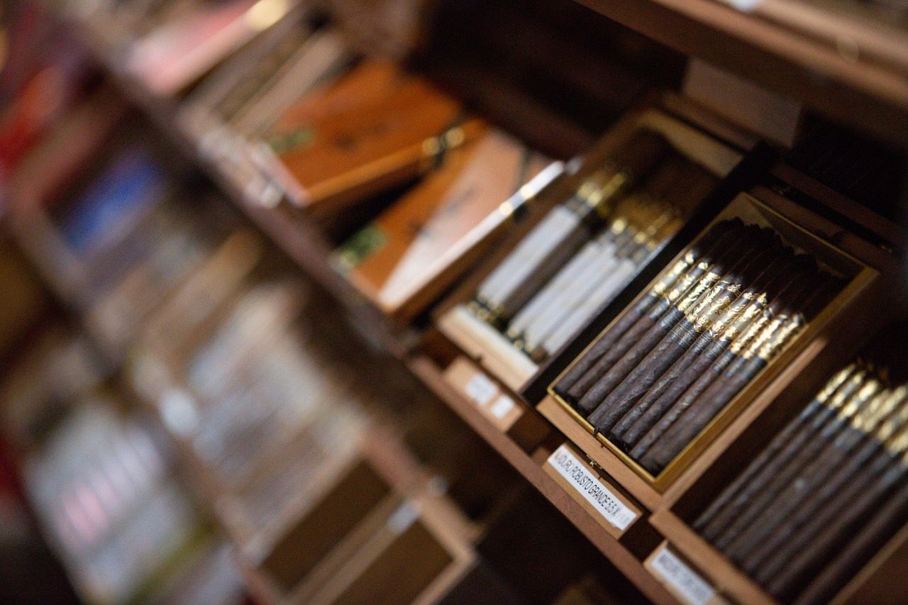 Boxes of cigars are lined up on a shelf in a store