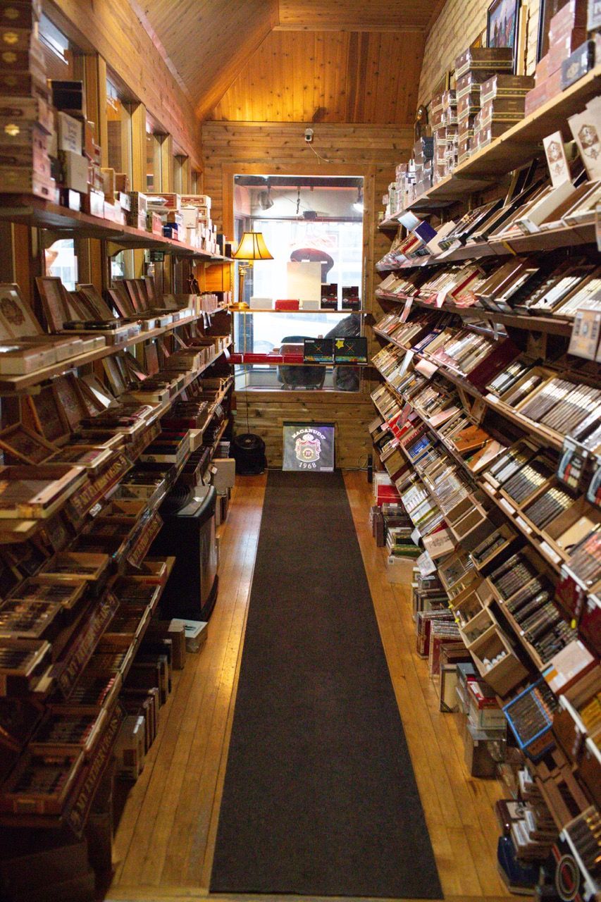 A long hallway humidor filled with shelves filled with lots of cigars.