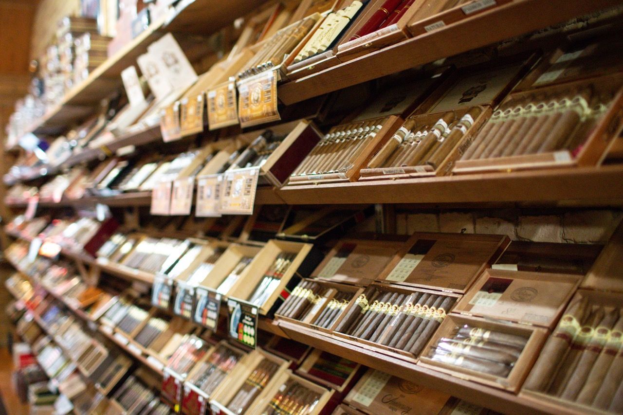 A humidor shelf filled with boxes of cigars in a store.