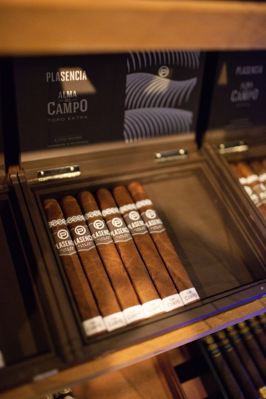 A box of cigars is sitting on a wooden shelf.