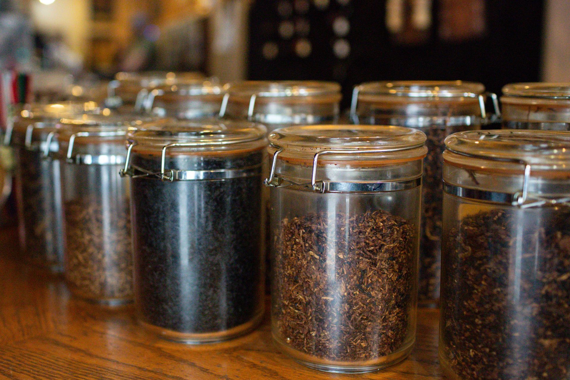 A row of glass jars filled with coffee beans on a wooden table.