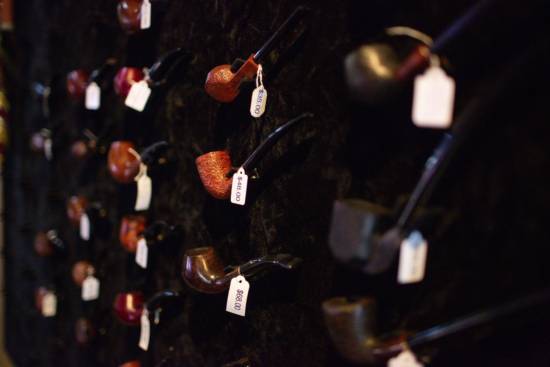 A bunch of pipes hanging on a wall with tags on them.
