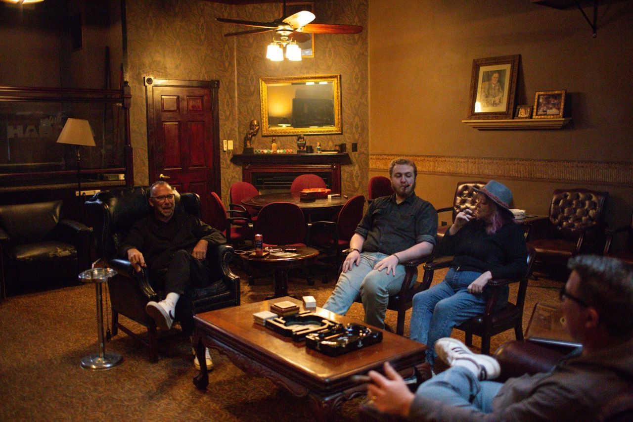 A group of people are sitting around a table in a cigar lounge