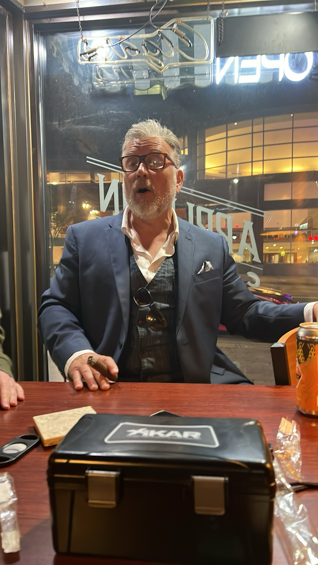 Dan Davies in a suit is sitting at a table with a box on it.