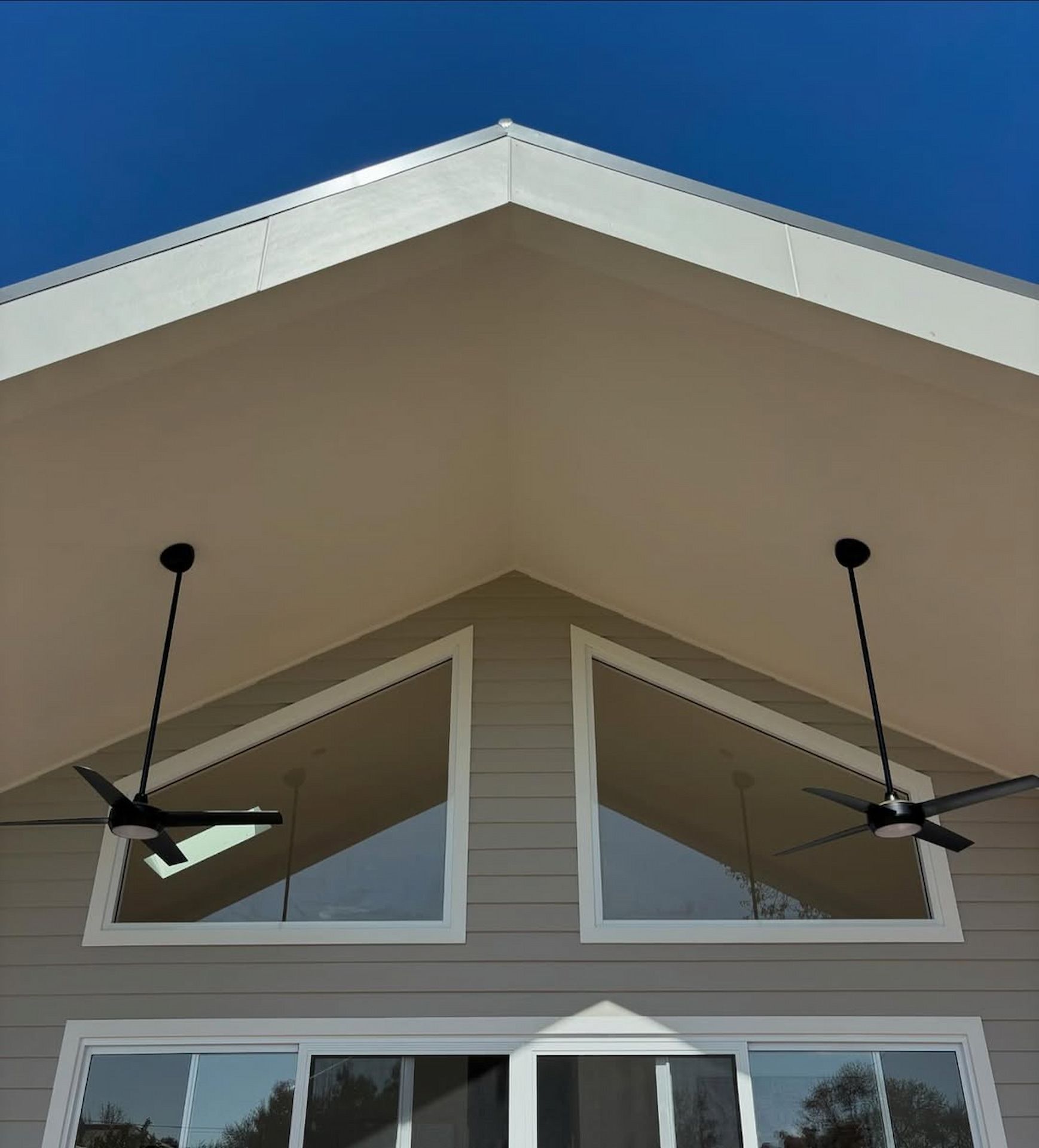 Beige and white building exterior with large triangular windows and ceiling fans against a blue sky — Nielsen Construction in Wagga Wagga, NSW