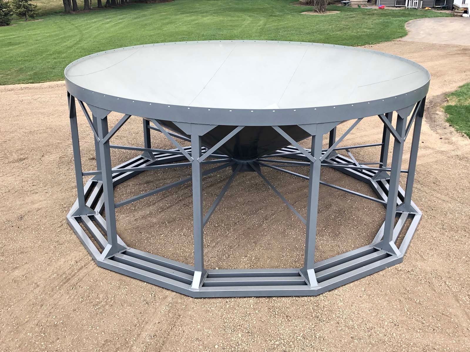 Round gray outdoor table with metal frame on gravel in a yard