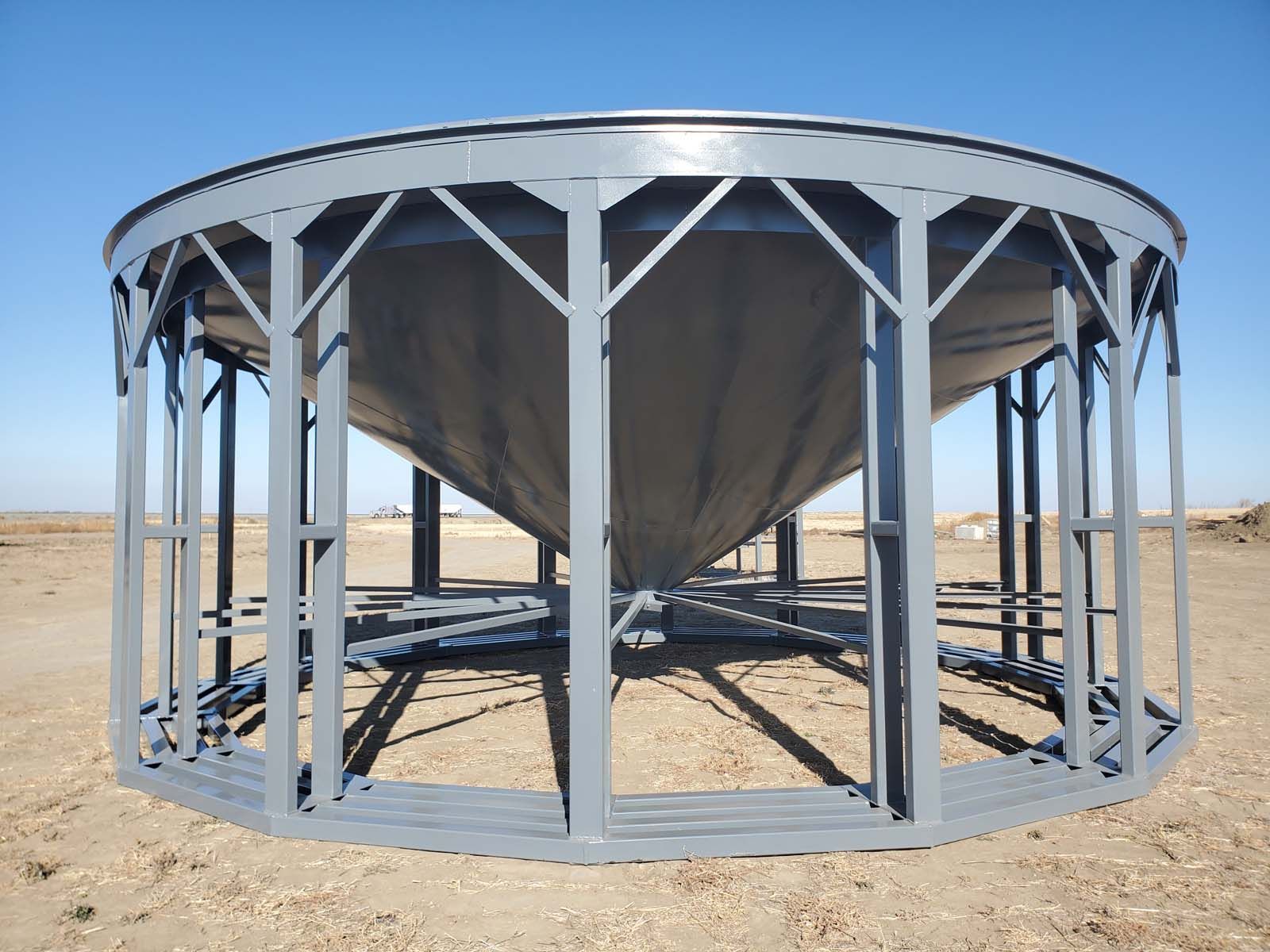 Large circular metal structure in a dry desert landscape, viewed from below