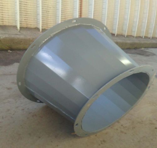 Gray metal duct or pipe fitting with flanged ends, resting on concrete outdoors.