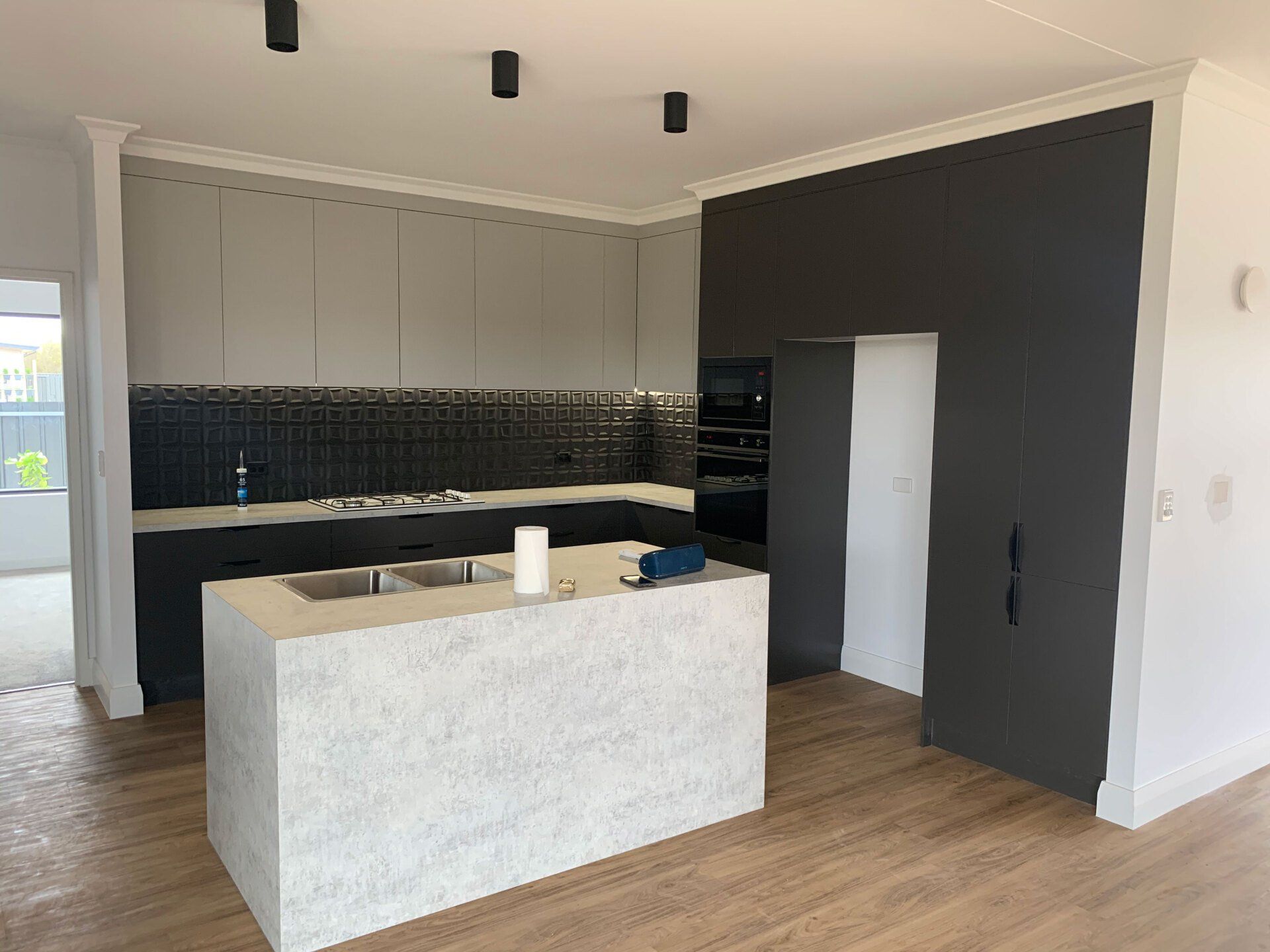 Modern kitchen with gray cabinets, island, and dark accent wall; light wood floors.