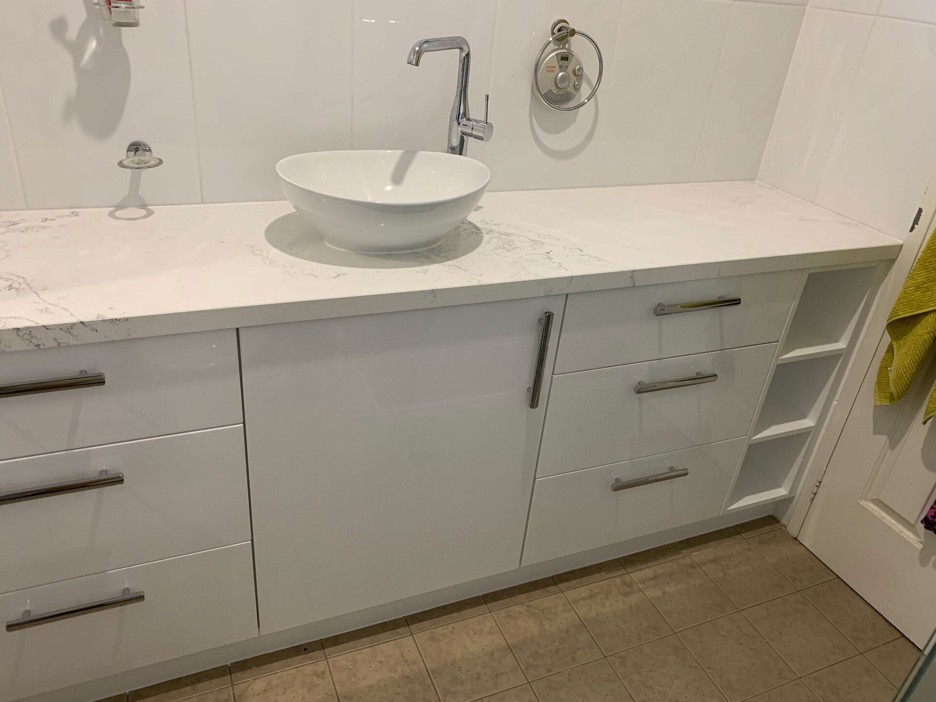 White modern bathroom vanity with vessel sink, chrome fixtures, and open shelving.