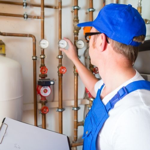 A man in a blue hat is working on a pipe