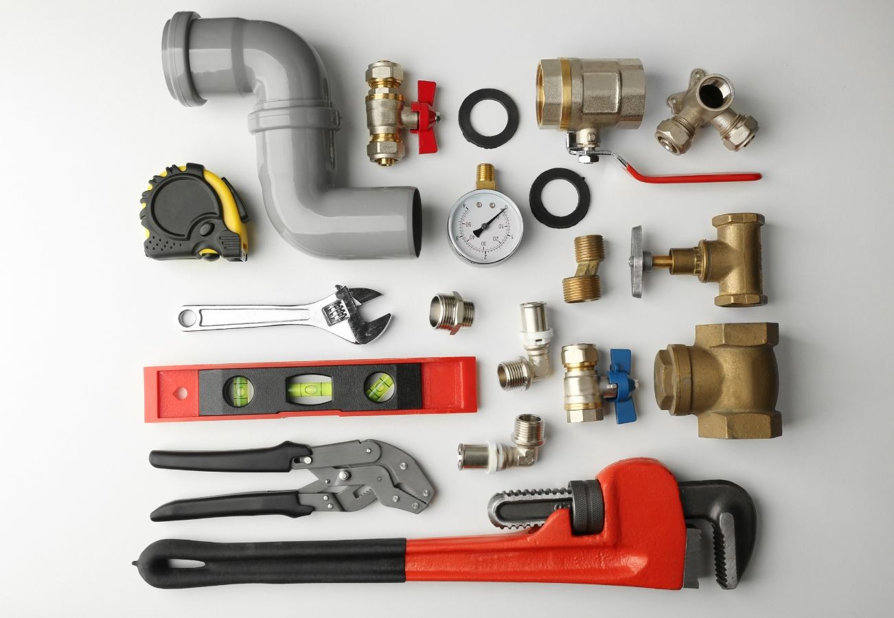 A bunch of plumbing tools are laying on a white surface.