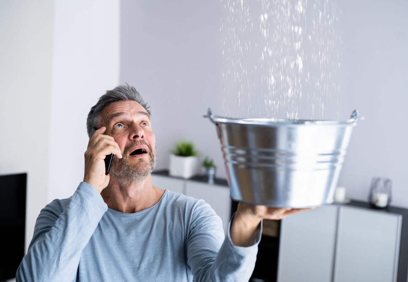A woman is kneeling under a sink talking on a cell phone.