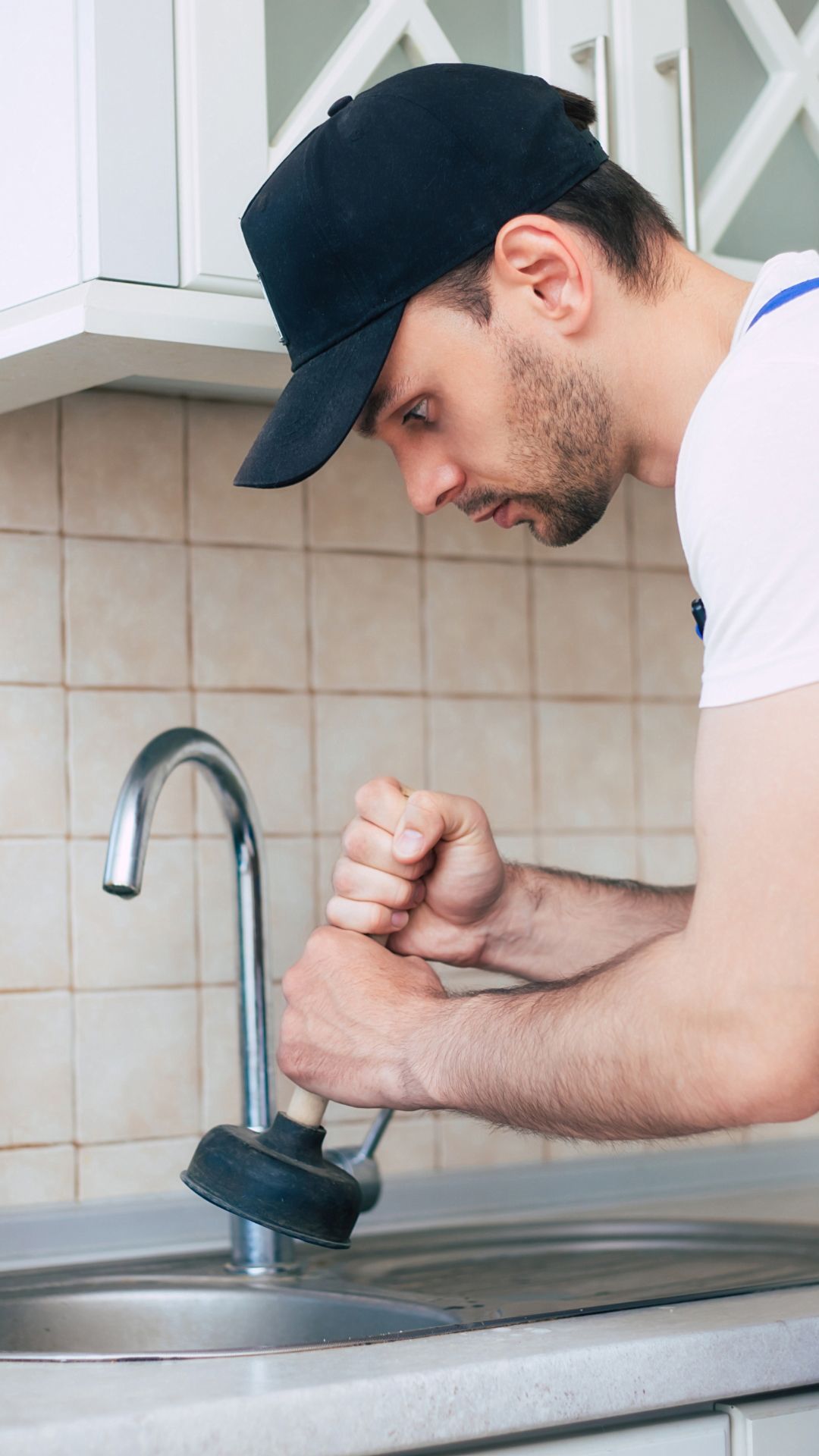 A man is fixing a sink with a plunger.