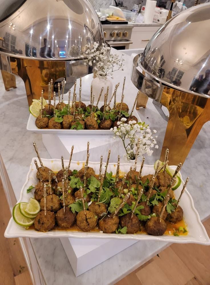 Buffet table with skewered appetizers on trays under silver serving domes