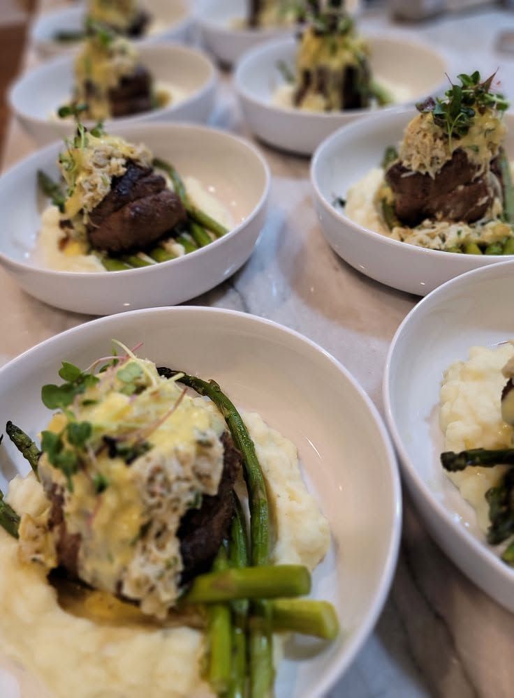 Small plated gourmet meals with green vegetables arranged on a table