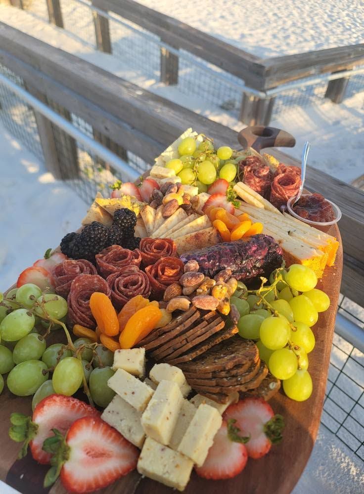 Charcuterie board with grapes, strawberries, dried apricots, nuts, crackers, and cheeses on a snowy table