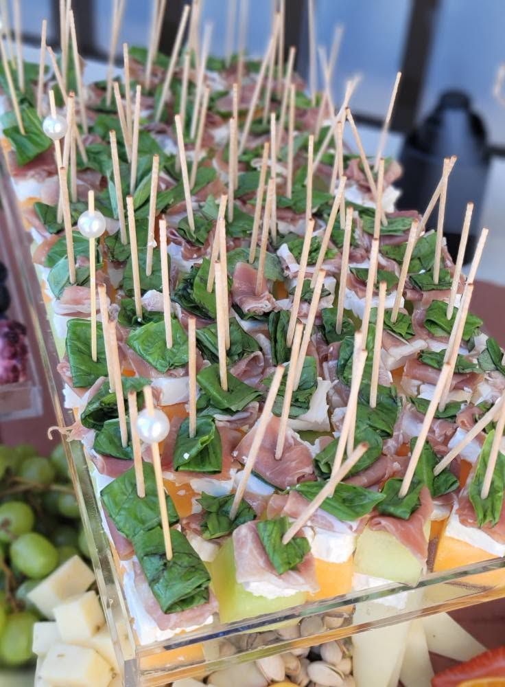 Assorted bite-size appetizers with toothpicks on a serving tray, topped with herbs and sauces