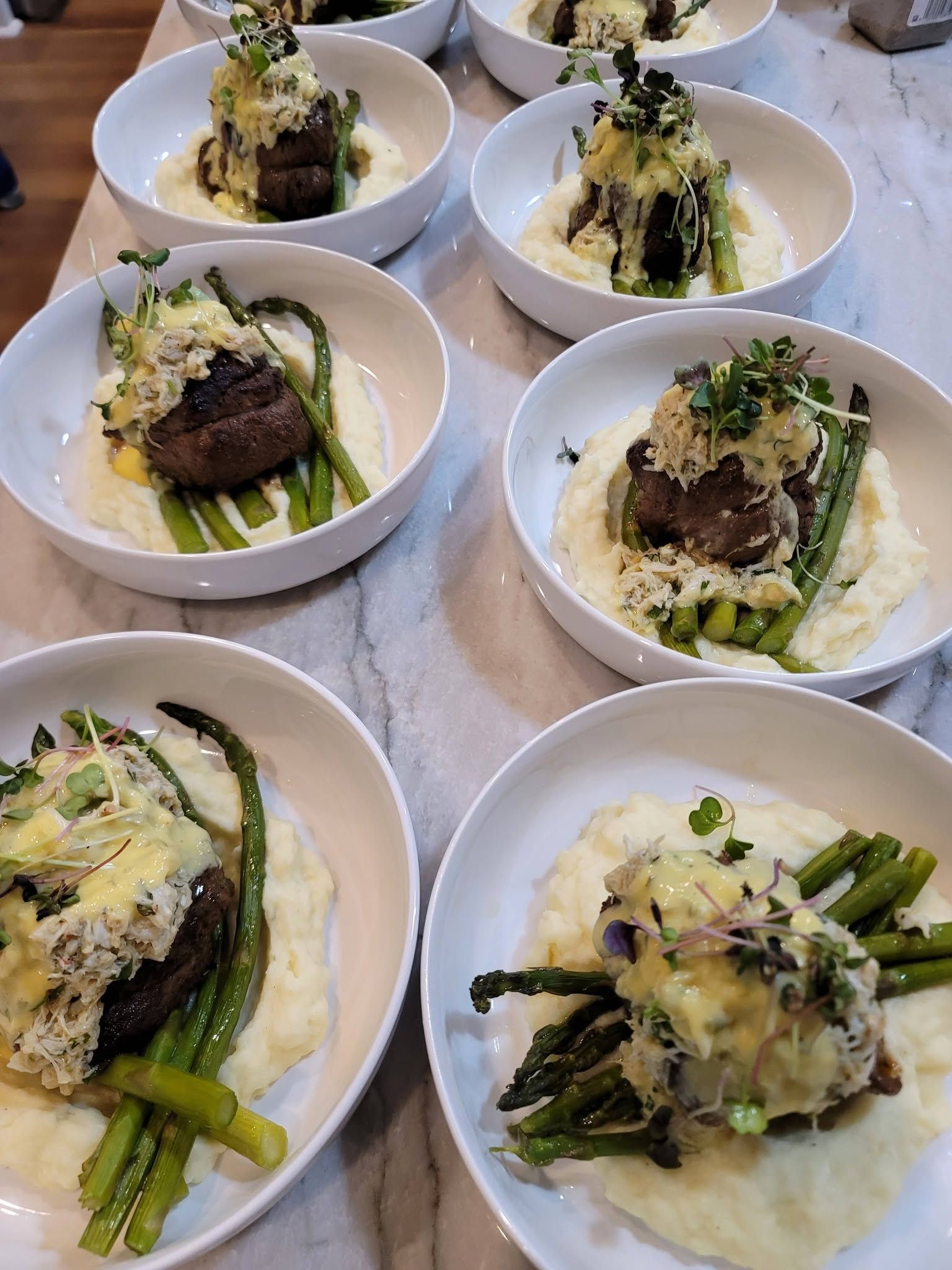 Plated gourmet beef and asparagus dishes topped with sauce, arranged on a table