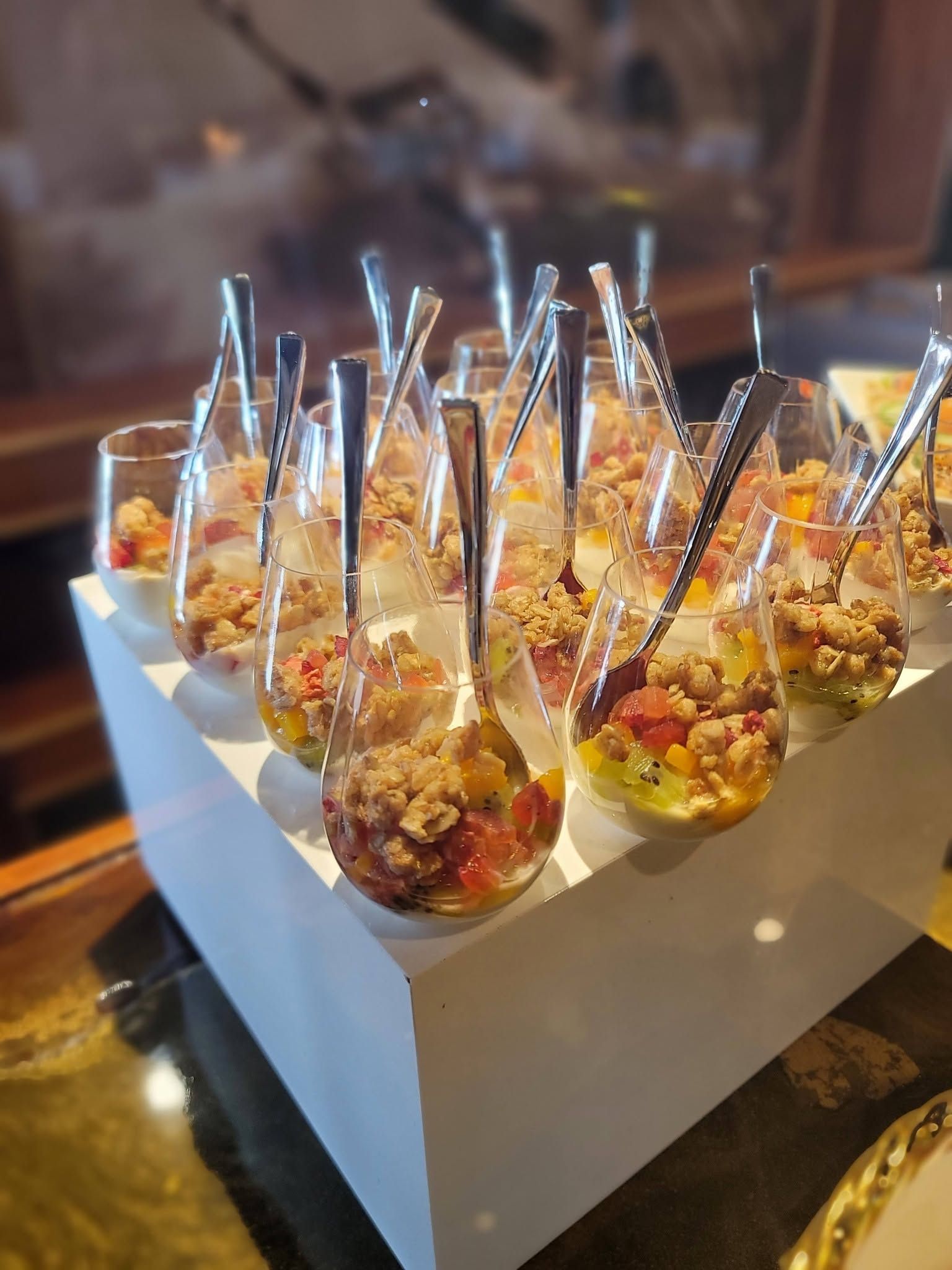 Assorted appetizer cups with spoons arranged on a white tray at a buffet table