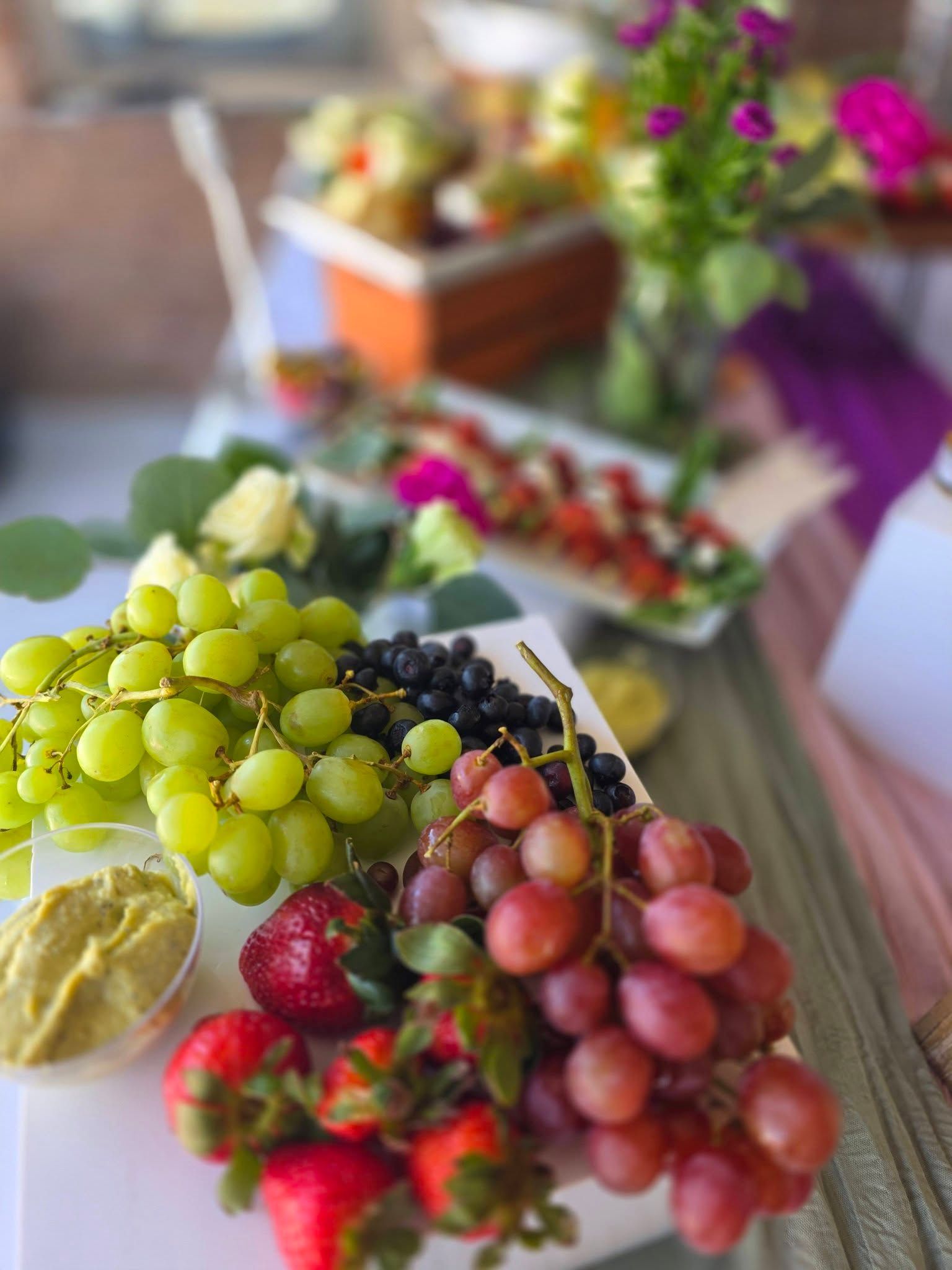Fruit platter with grapes, strawberries, blackberries, and a bowl of dip on a table