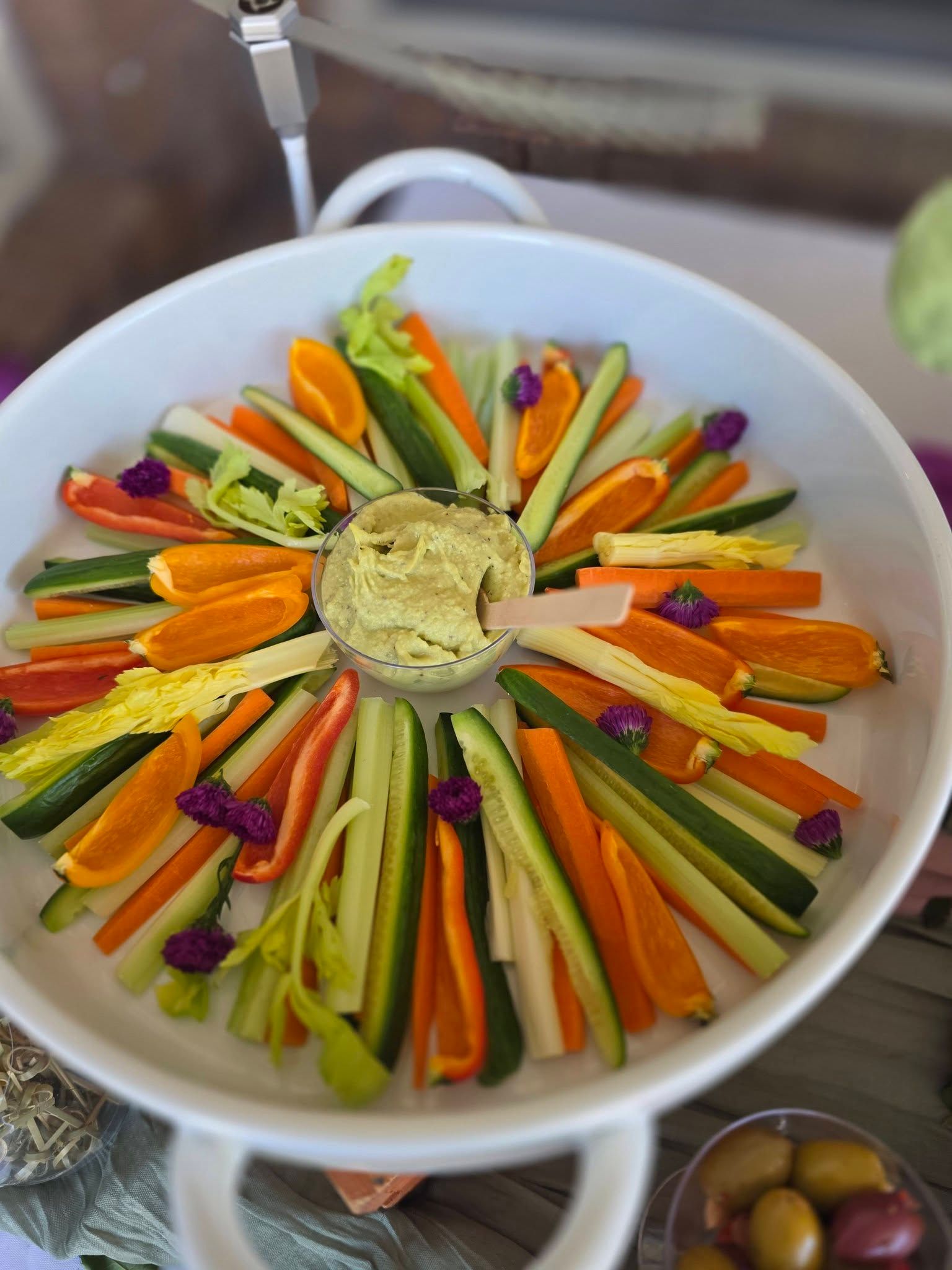 Vegetable platter arranged in a circle around a bowl of dip on a white tray
