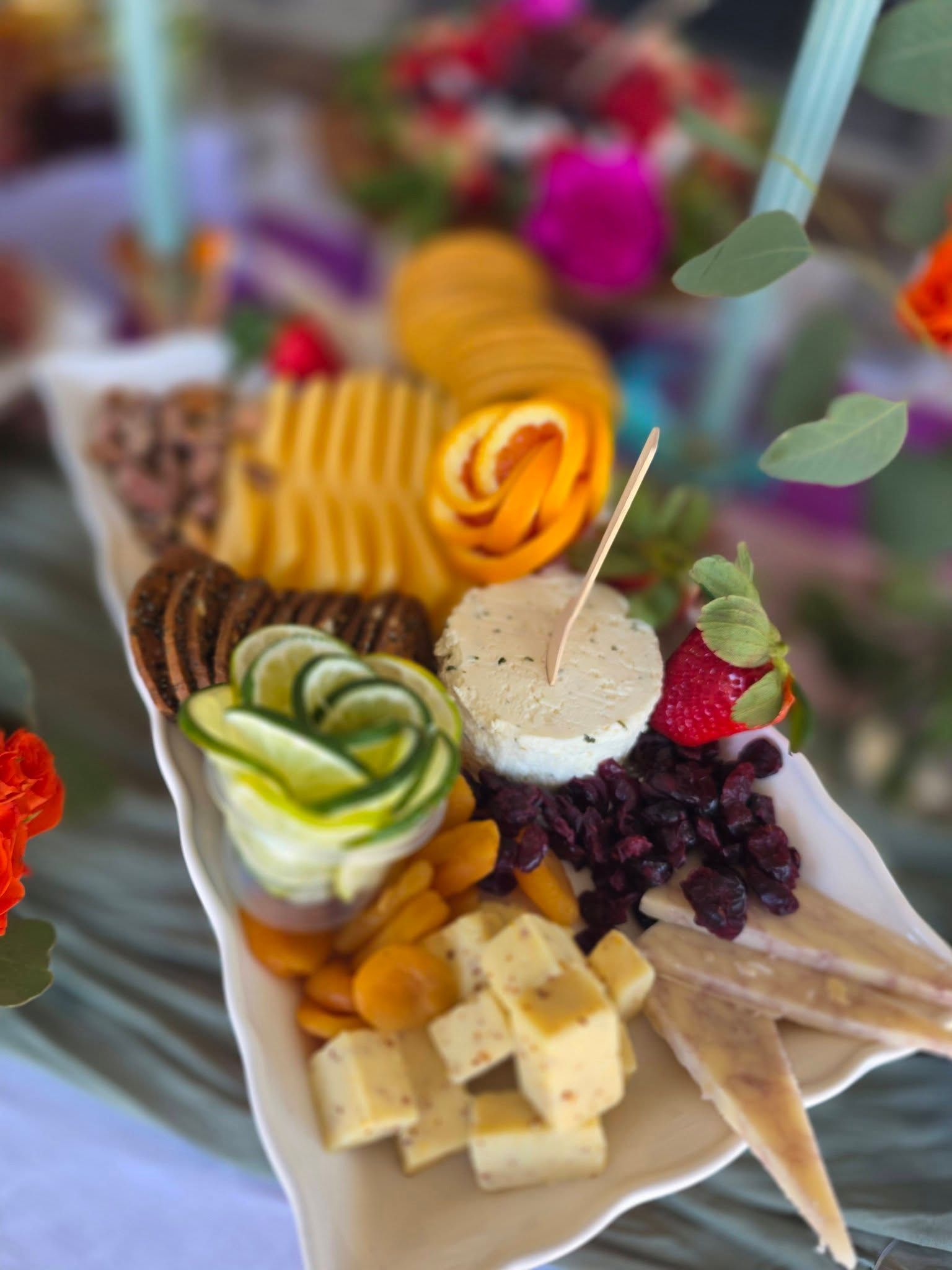 Colorful charcuterie board with fruit, cheese, crackers, and vegetables on wooden trays