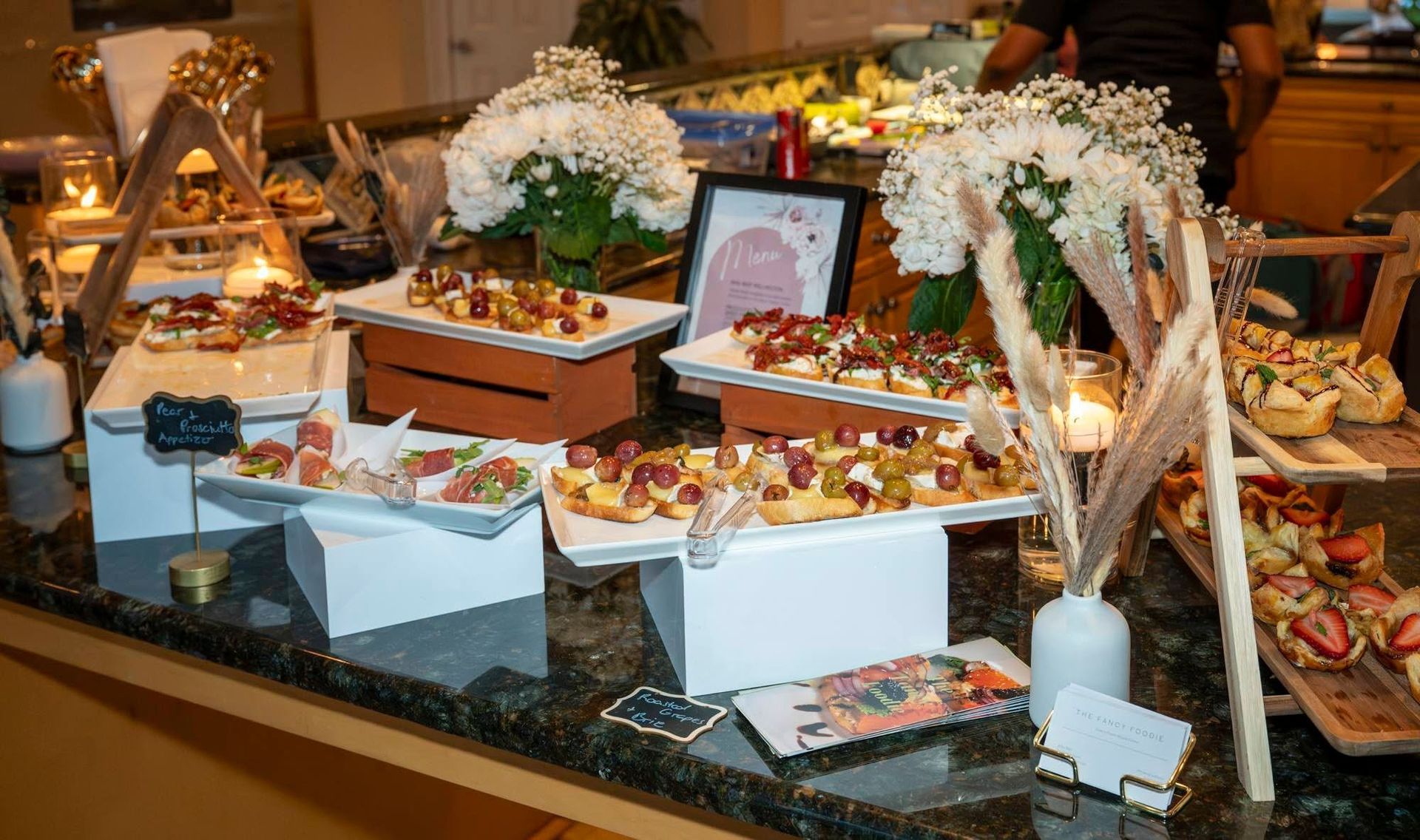 Elegant buffet spread with pastries, fruit, and white floral decor on a banquet table